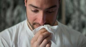 man with seasonal allergies holding tissue to nose
